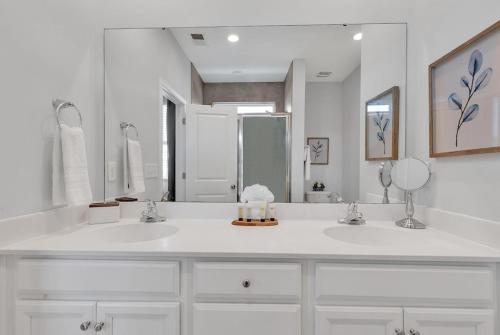 a white bathroom with two sinks and a large mirror at Centrally Located Myrtle Beach House Near Sports Center, Broadway at the Beach, Shopping, Beach, and Golf in Myrtle Beach