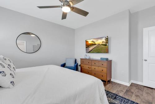 a white bedroom with a ceiling fan and a dresser at Centrally Located Myrtle Beach House Near Sports Center, Broadway at the Beach, Shopping, Beach, and Golf in Myrtle Beach