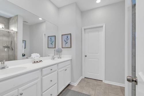 a white bathroom with a sink and a mirror at Centrally Located Myrtle Beach House Near Sports Center, Broadway at the Beach, Shopping, Beach, and Golf in Myrtle Beach
