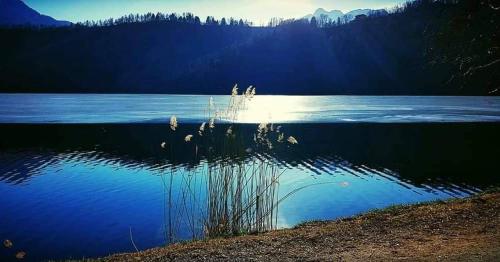 a view of a lake with the sun reflecting on the water at Antica Dimora in Levico Terme