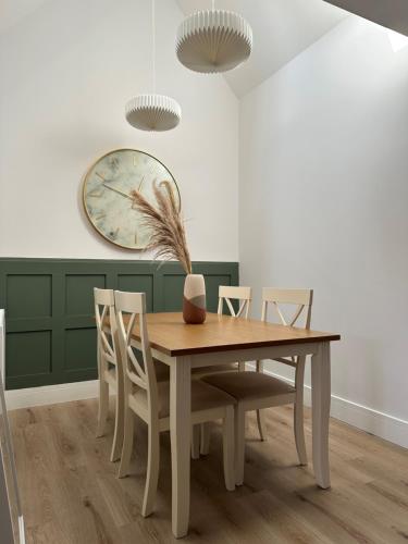 a dining room table with chairs and a clock on the wall at Luxury Modern Cotswold Cottage in Stow on the Wold