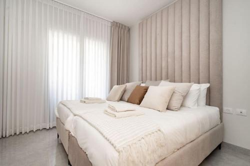a white bedroom with a large bed with white pillows at Lovely 1 bedroom apt w/pool. Haneviim st jerusalem in Jerusalem