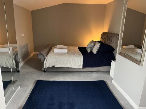 a bedroom with a bed with a mirror and a blue rug at Silver Dream in Southend-on-Sea