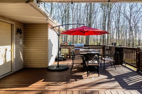 a patio with a table and a red umbrella at Blue Mountain Lake Pocono House in East Stroudsburg