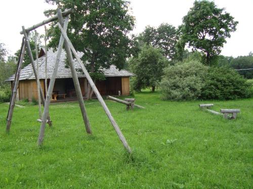 a wooden house in a grassy field with a swing at Līgatnes Zemturi in Augšlīgatne