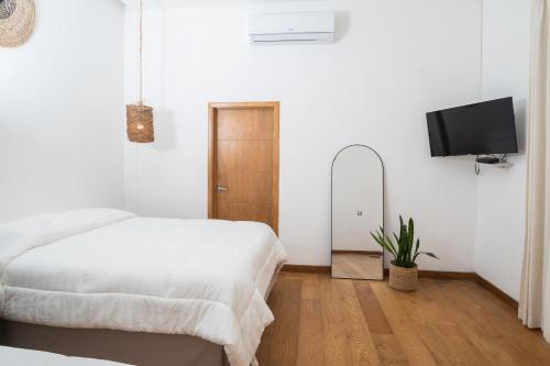 a white bedroom with a bed and a flat screen tv at Equinoccio Hotel in Santa Ana