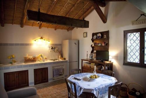 a kitchen with a table and a white refrigerator at La casa del Cavaliere in Santa Maria di Licodia