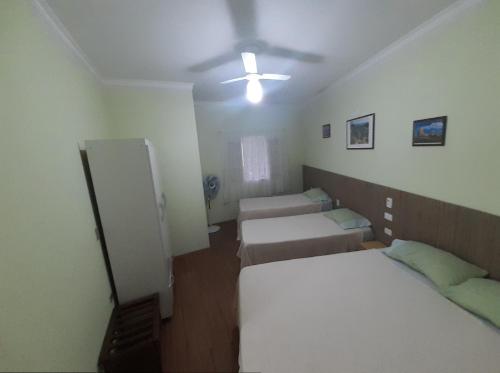 a room with three beds and a ceiling fan at Apartamento São Pedro SP in São Pedro