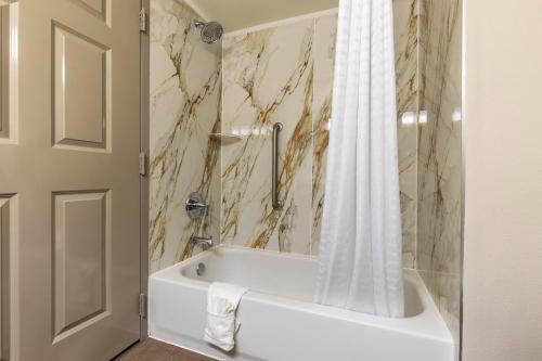 une salle de bain avec une baignoire blanche et un rideau de douche dans l'établissement Wingate by Wyndham Lafayette Airport, à Lafayette