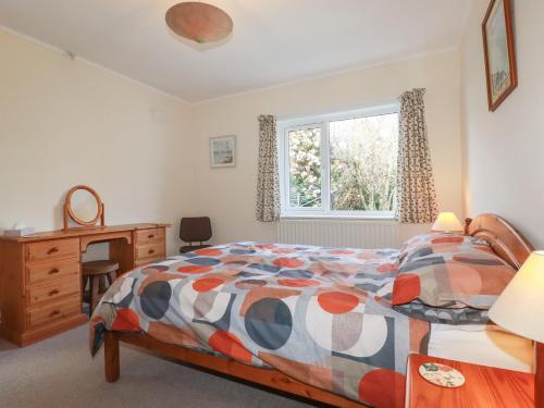 a bedroom with a bed and a desk and a window at 5 Carlyon Road in Truro