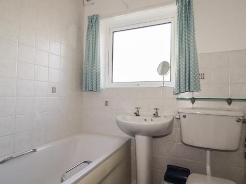 Un baño con lavabo, bañera y ventana. en 5 Carlyon Road, en Truro
