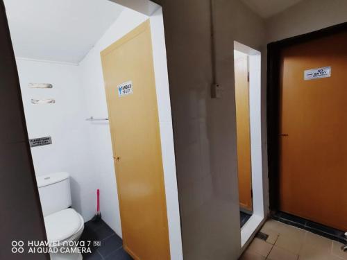 a bathroom with a toilet and a brown door at MK AL-ATTAS HOMESTAY - KUALA BESUT in Kampong Nail