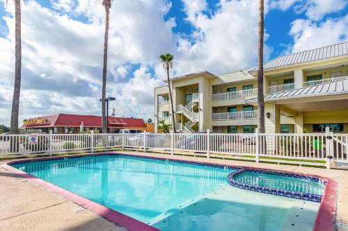 a swimming pool in front of a hotel with palm trees at Studio 6-Corpus Christi, TX - North in Corpus Christi