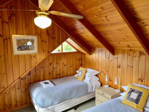 a bedroom with two beds in a wooden cabin at Ti-Tree Village in Ocean Grove