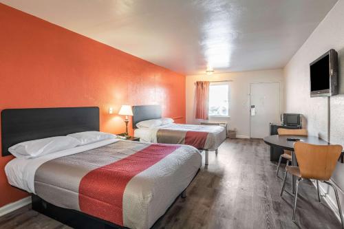 Habitación de hotel con 2 camas, mesa y TV en Motel 6-Portsmouth, VA, en Portsmouth