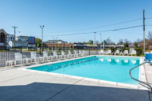 a swimming pool with white chairs and a fence at Motel 6-Portsmouth, VA in Portsmouth
