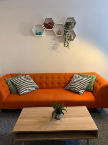 an orange couch in a living room with a table at Gorgeous seaside getaway. in Hastings