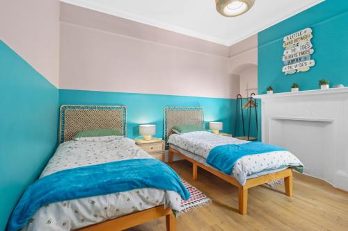 two beds in a room with blue and white walls at Clinton Place in Seaford
