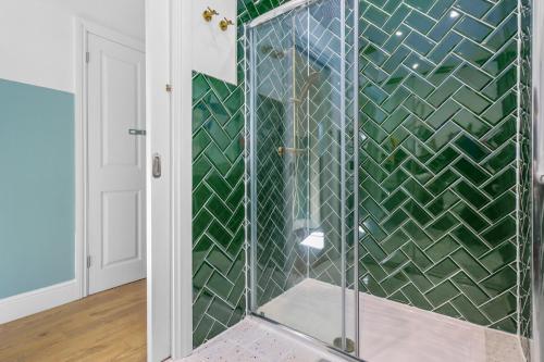 a shower in a bathroom with green tiles at Clinton Place in Seaford