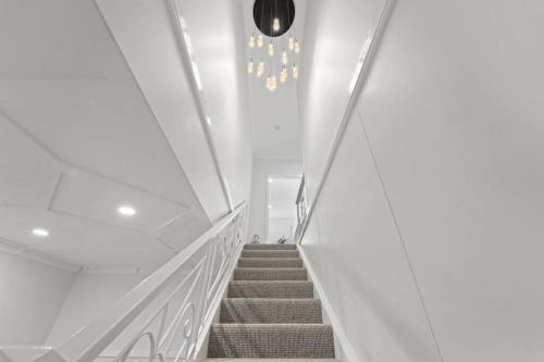 a staircase in a building with a chandelier at Sky Home - Two Bedroom Loft Townhouse with Bay Views in Sydney
