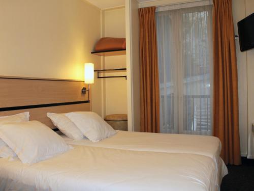 a hotel room with a large white bed and a window at New Hotel Saint Lazare in Paris