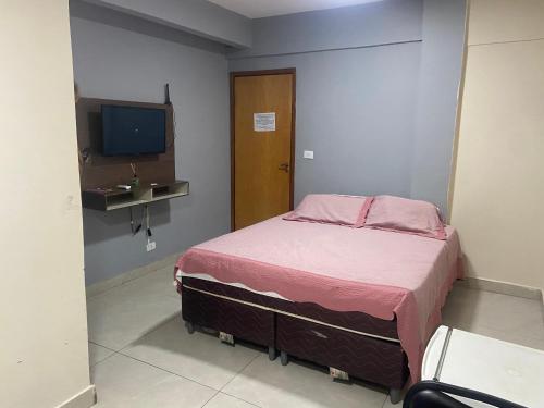 une petite chambre avec un lit et une télévision dans l'établissement El Nassr suits, à Goiânia