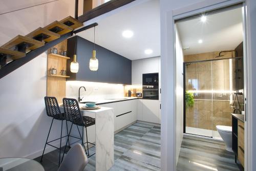 een keuken met witte kasten en een tafel en stoelen bij Cuencaloft Buenavista in Cuenca