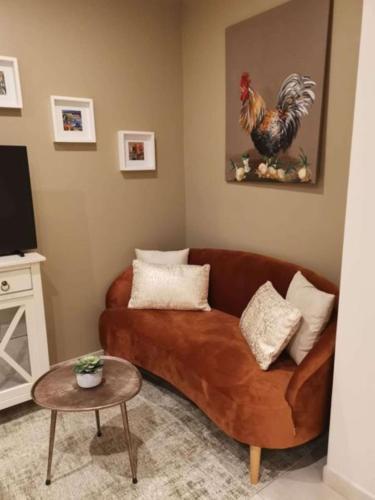 a living room with a brown couch and a chicken on the wall at Best Western Grand Hotel de Bordeaux in Aurillac
