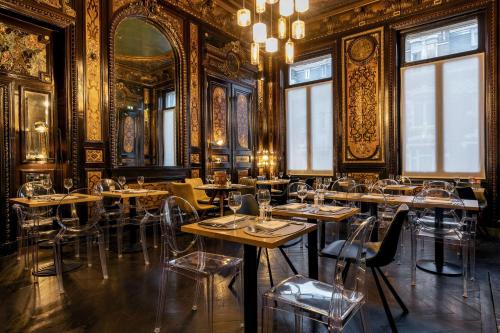 a restaurant with tables and chairs in a room with gold walls at Best Western Urban Hotel in Lille
