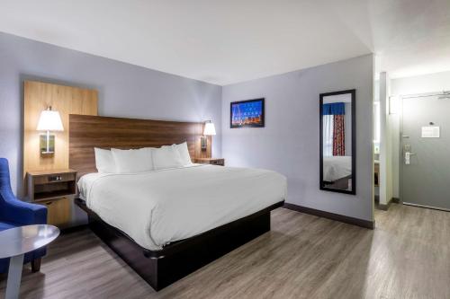 a hotel room with a large bed and a blue chair at Best Western Plus St. Louis West-Westport in Maryland Heights