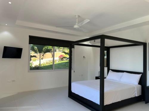 a bedroom with a black canopy bed and a window at The Indianna ~ Luxury Pool & Spa in Whitehouse
