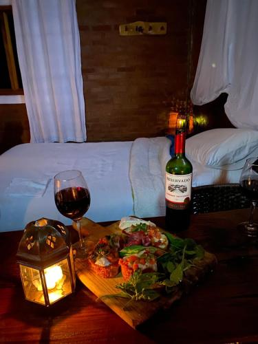 a table with a bottle of wine and a plate of food at Recanto do Leão in Alagoa