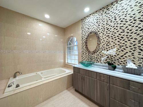 a bathroom with a tub and a sink and a mirror at Spacious and Luxurious 4bd 3br House Pool Tub BBQ Private in Miami