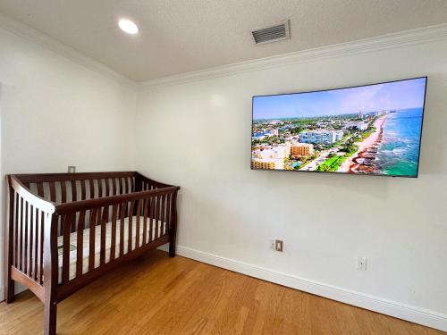 a room with a crib and a tv on a wall at Spacious and Luxurious 4bd 3br House Pool Tub BBQ Private in Miami