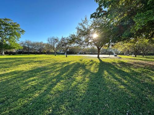 a park with a tree and its shadow on the grass at Spacious and Luxurious 4bd 3br House Pool Tub BBQ Private in Miami