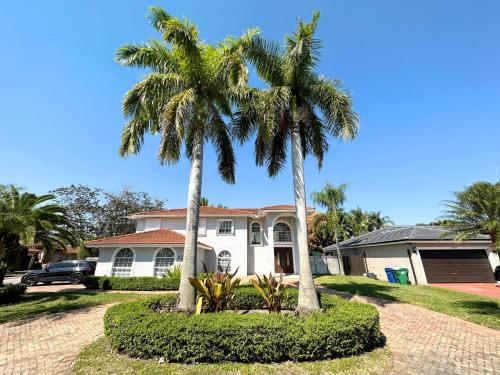 two palm trees in front of a house at Spacious and Luxurious 4bd 3br House Pool Tub BBQ Private in Miami