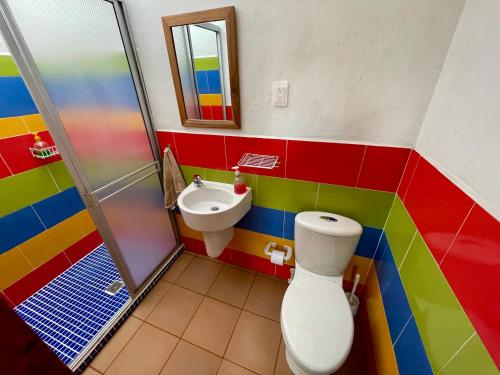 Baño colorido con aseo y lavamanos en Hostal Tralala Salento, en Salento