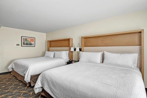 two beds in a hotel room with white sheets at Holiday Inn - Piscataway - Somerset by IHG in Piscataway