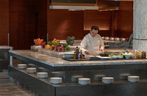 a man is preparing food in a kitchen at Le Meridien Bangkok in Bangkok