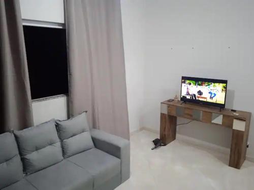 a living room with a couch and a table with a tv at AP 22 hortência in Poços de Caldas