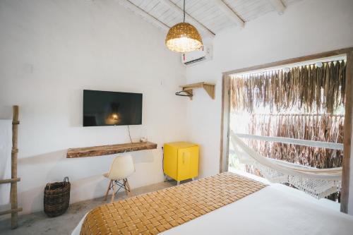 een slaapkamer met een bed, een tv en een raam bij Pousada Villa Cacau in Trancoso