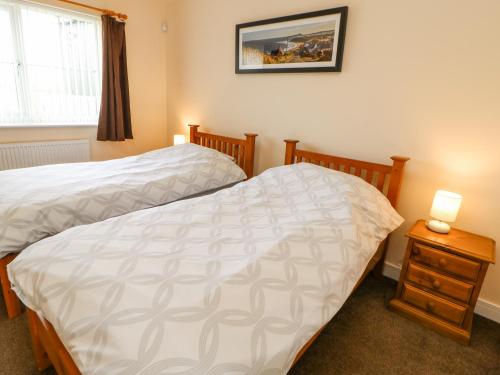 a bedroom with two beds and a nightstand and a window at Wansbeck in Longframlington