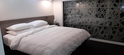 a bedroom with a bed with white sheets and pillows at Impressive Central Apartment in Warrnambool