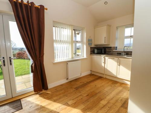 a kitchen with white cabinets and a large window at Coquet in Longframlington