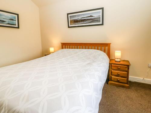 a bedroom with a white bed and two night stands at Coquet in Longframlington