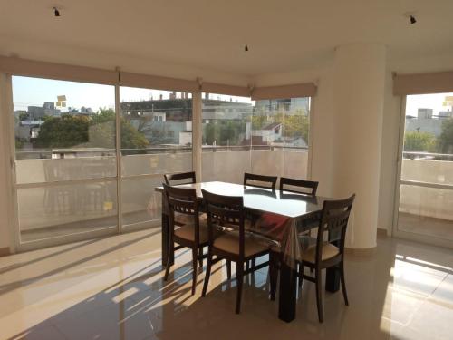 une salle à manger avec une table, des chaises et des fenêtres dans l'établissement Edificio Leonardo departamento 16, à Villa Carlos Paz