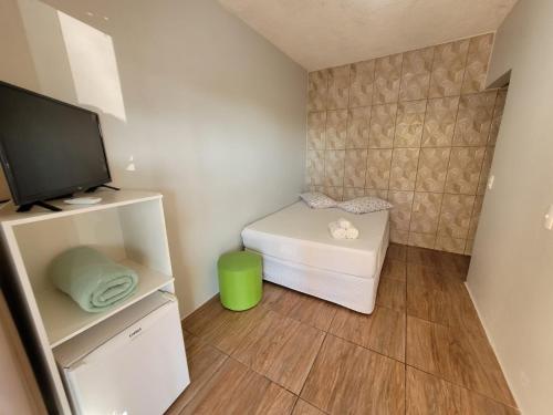 Habitación pequeña con TV y mesa pequeña. en Suítes Recanto Praia Grande, en Penha