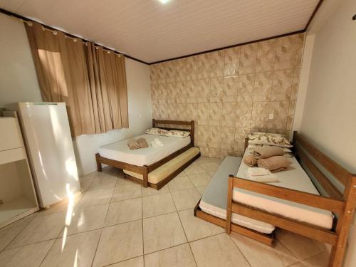 Habitación con 2 camas y nevera. en Suítes Recanto Praia Grande, en Penha