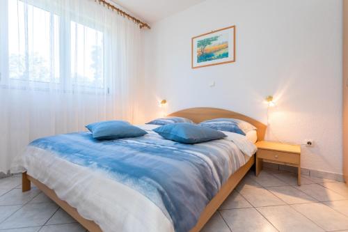 ein Schlafzimmer mit einem großen Bett mit blauen Kissen in der Unterkunft Apartments with a parking space Njivice, Krk - 20504 in Njivice