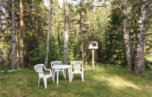 three chairs and a table in a yard with a bird feeder at 2 Bedroom Nice Home In Årjäng in Årjäng